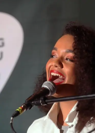 A young woman singing into a microphone.