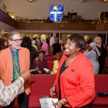 Three people smiling and talking inside the church with the stained glass window in the background.