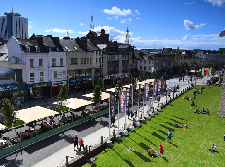 A view of central Cardiff with people sitting on the grass.