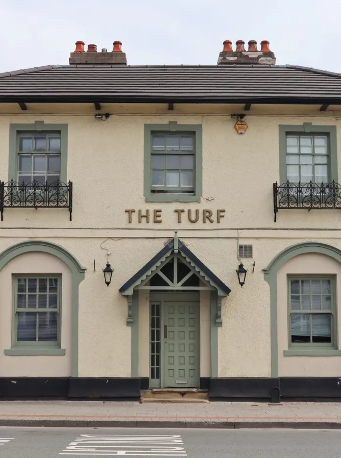 Un panneau montrant un visage souriant portant un bob, avec le texte "ALWAYS SUNNY WREXHAM TURF-TROPICANA"