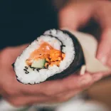 A hand holding a roll of sushi