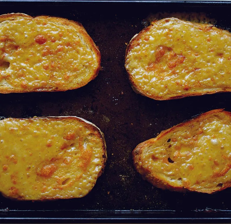 A baking tray with slices of freshly grilled Welsh rarebit