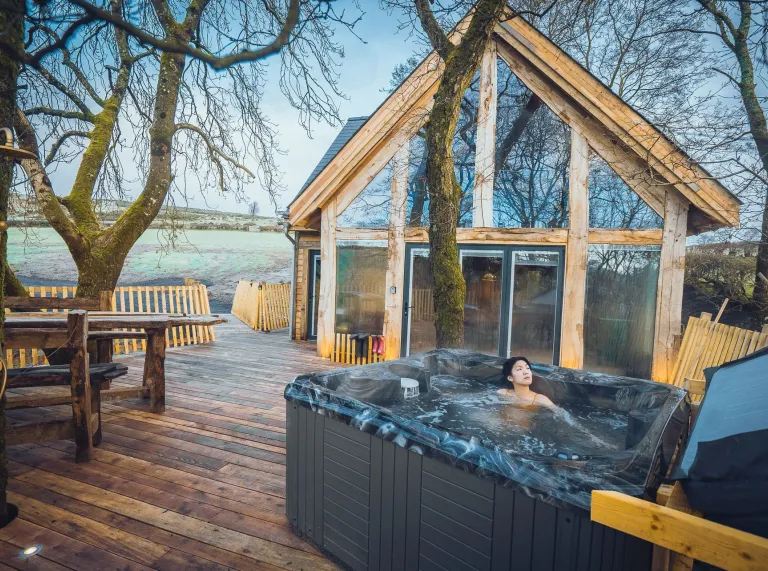 A person in a hot tub on the treehouse.
