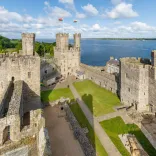 A picture of Caernarfon Castle, showing the inside lawn within the castle and the sea in the backdrop