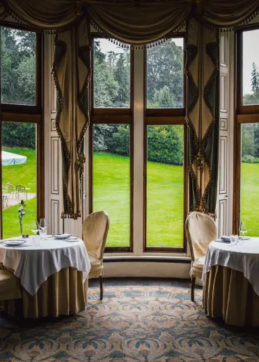 Tables in the restaurant looking out to a green garden.
