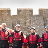 Four people standing in front of a stone wall.