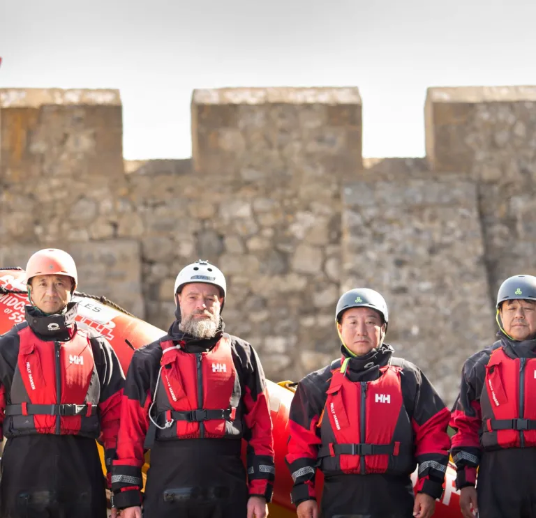 Four people standing in front of a stone wall.