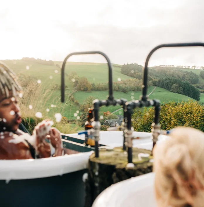 Two people in two hot tubs at a luxury retreat.