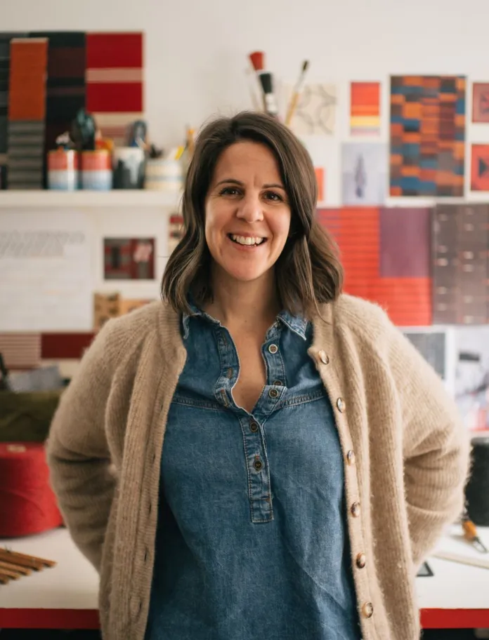 Welsh textile artist Llio James standing at her desk in her studio