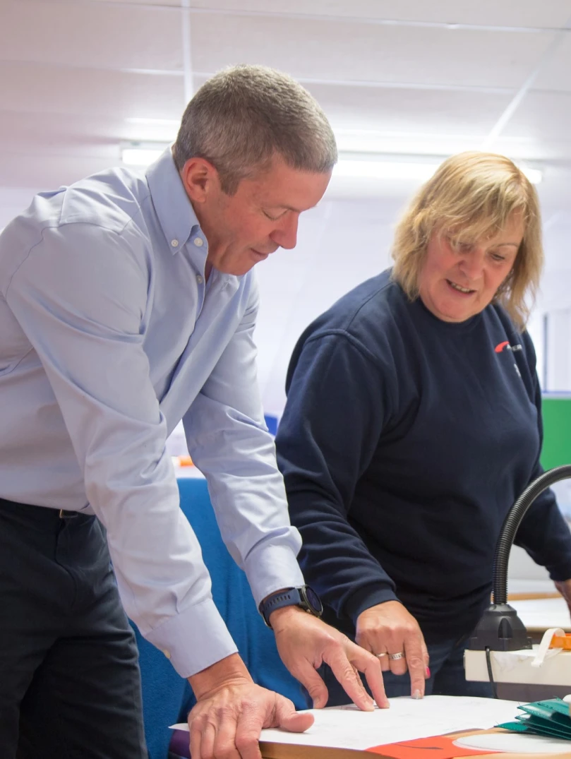 Two people consulting product plans on a table