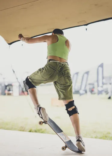 A person performing a skateboard trick in a festival tent