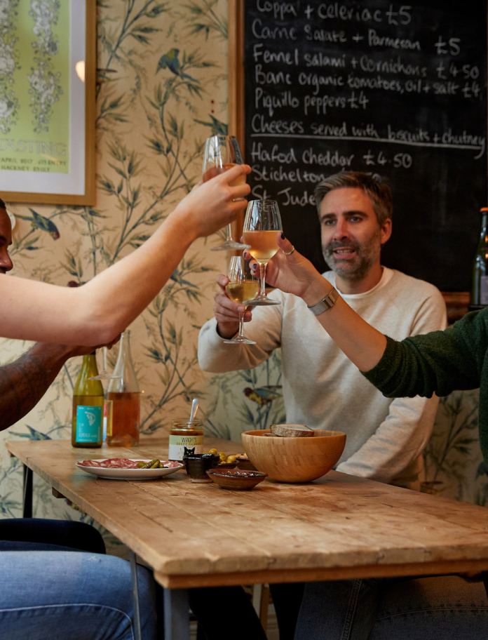 group of people sat at table, making a toast with drinks