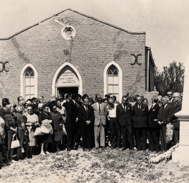 large group of people around memorial outside chapel.