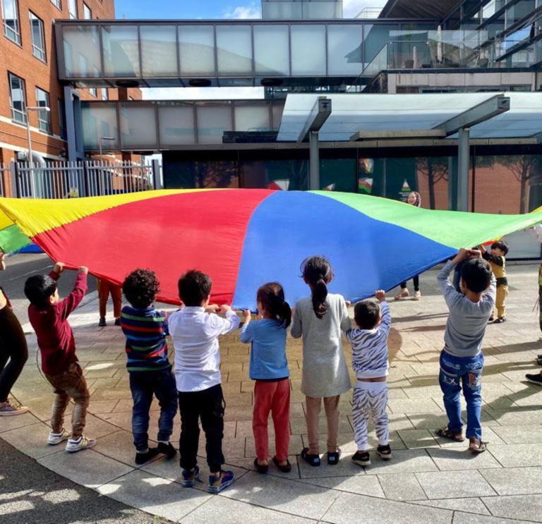 A group of children playing with a parachute.