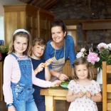 A woman in her kitchen surrounded by her three young children