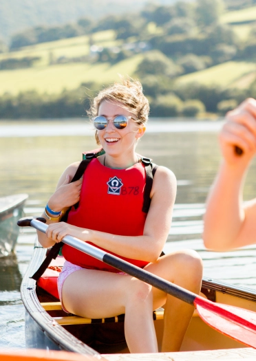 A woman sitting on a canoe on the water.