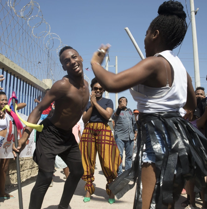 A group of people outside, dancing in the sunshine.