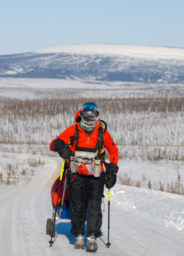 Foreground is female adventurer background is a snowy landscape