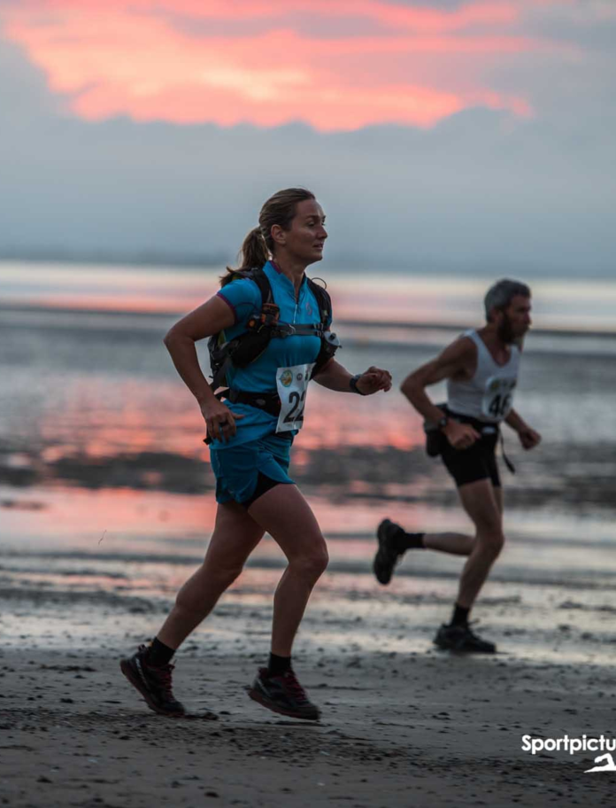 beach with woman running in foreground with man in background
