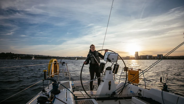 Hannah Mills at the wheel of the yacht, sailing in Cardiff Bay
