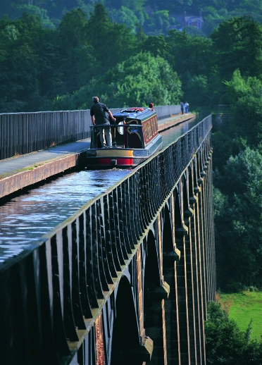 Man in a boat crossing a canal viaduct