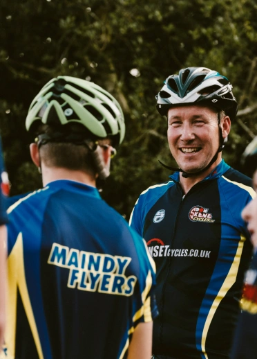 cyclists in team cycling clothing smiling at team mates
