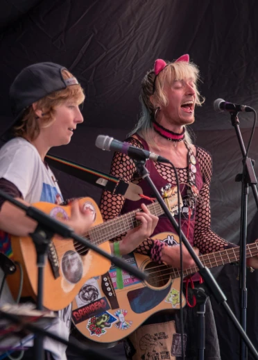 Two people playing guitars and signing on stage