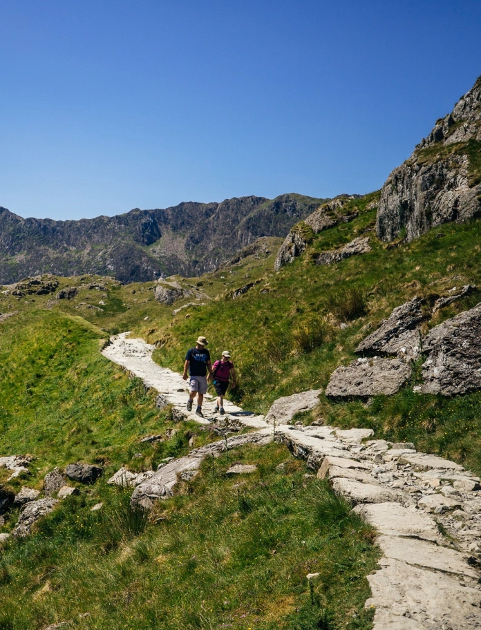 Two people walking along a trail in the mountains