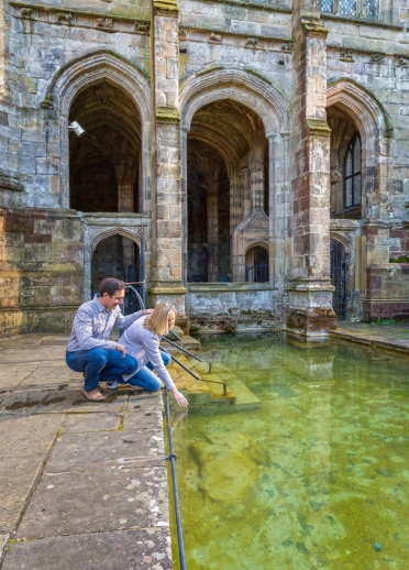 Two people putting their hands into the water.