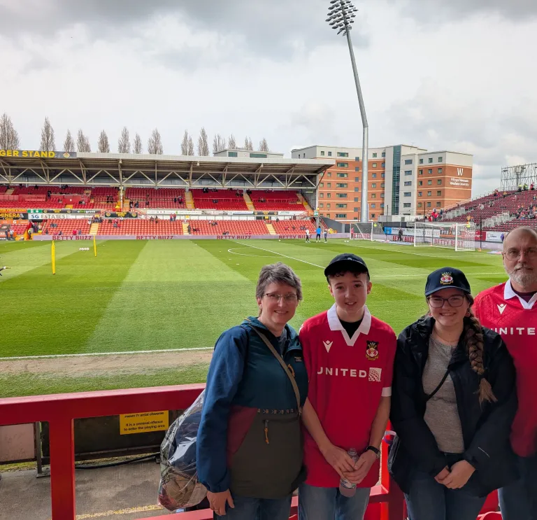 Four people wearing Welsh football shirts standing inside the stadium