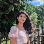 A young girl stood in pink dress smiling in front of forest