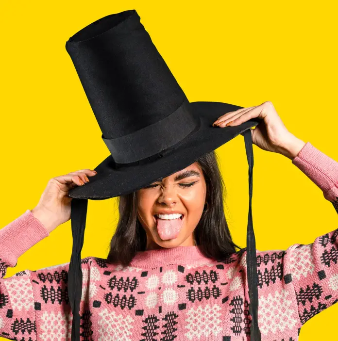 A girl with a Welsh woollen style jumper wearing a traditional tall black Welsh hat 