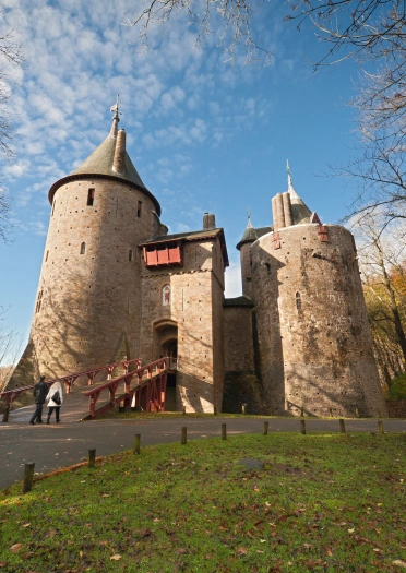 An external view of a large castle against the backdrop of a forest