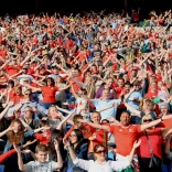 A crowd of people at a football game singing the national anthem.