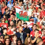 A crowd of people and a Welsh flag. 
