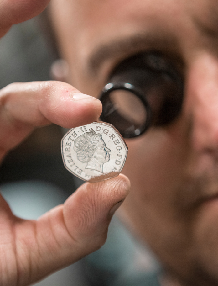 close inspection of a newly minted fifty pence coin at Royal Mint, Llantrisant