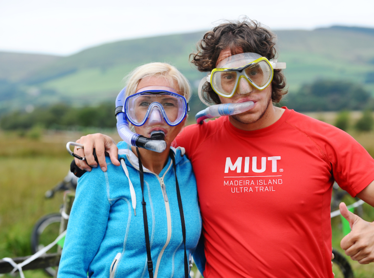 Homme et femme enlacés, tous les deux avec des tubas, colline flou à l’arrière-plan