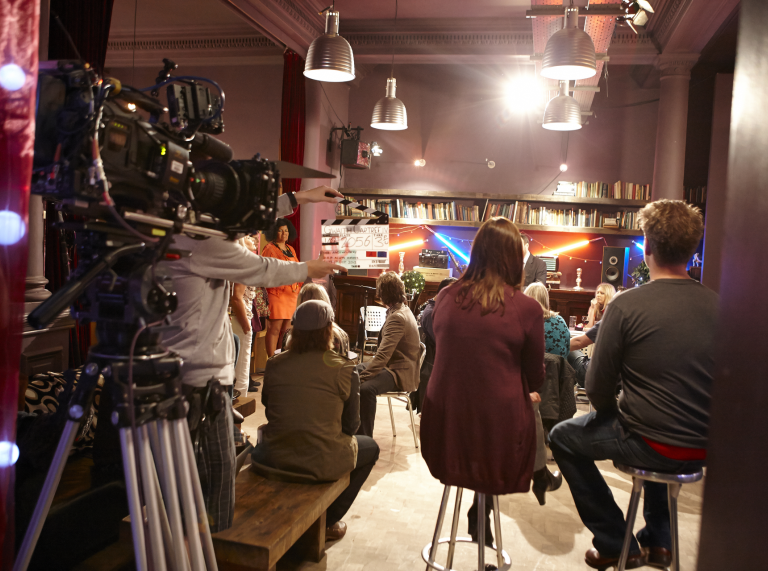 filming of actors taking place in a television studio on a drama set