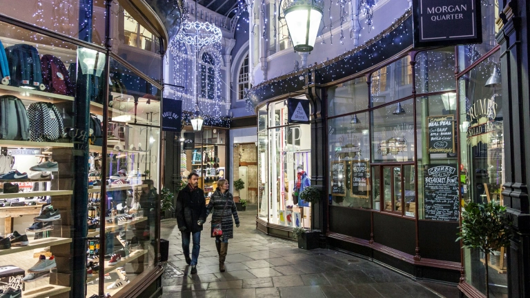 People walking through Victorian shopping arcade decorated with Christmas lights.