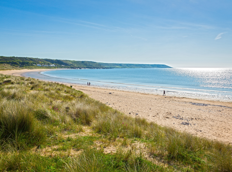 coastal scenery: sunny day, distance figures walking on beach