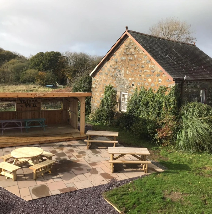A pub garden with a shelter and outside seating on a patio.