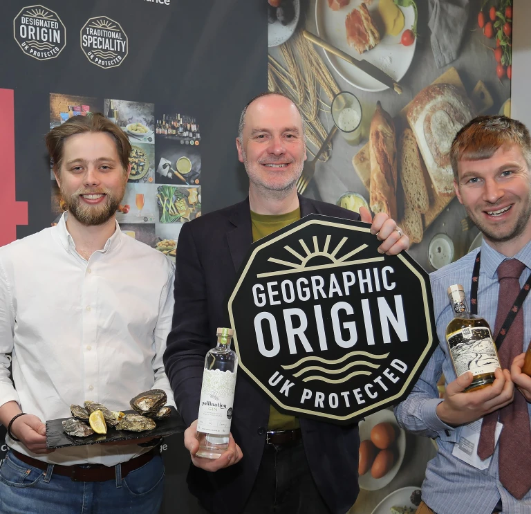Three men holding their products smiling at the camera.
