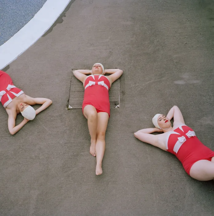 Three people lying on the ground with their hands behind their backs.