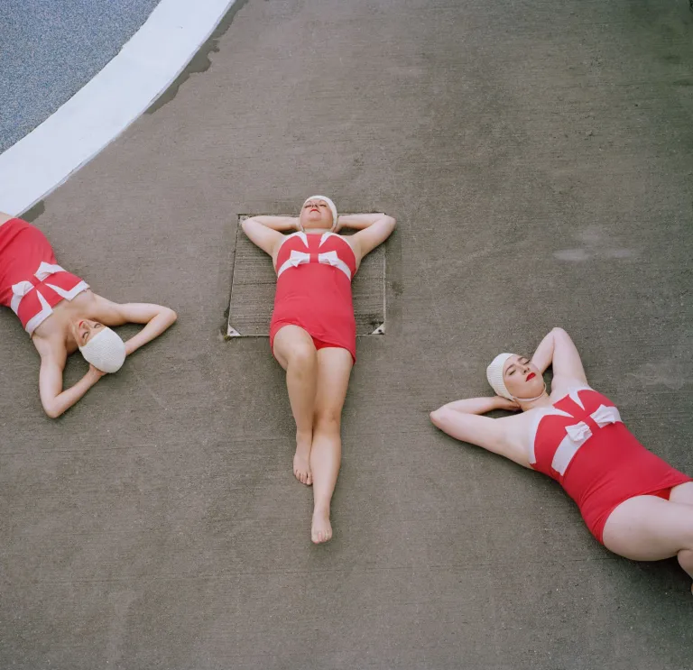 Three people lying on the ground with their hands behind their backs.