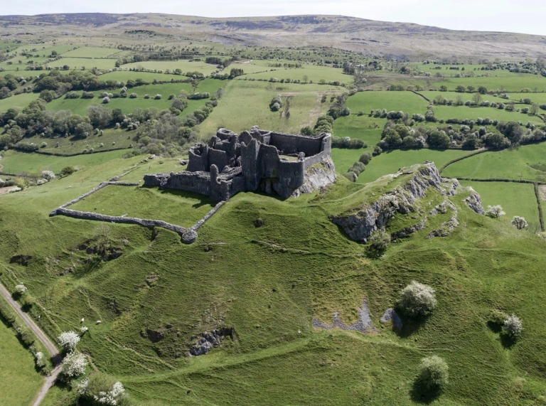 Castle ruins surrounded by green fields and mountains
