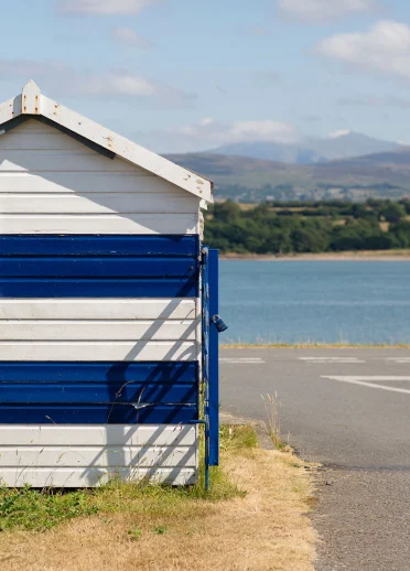 Blue and white striped beach hut on the Menai Strait