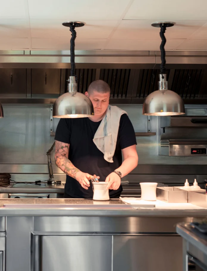 Eine Küche mit einem Mann (Koch) der Speisen herrichtet.