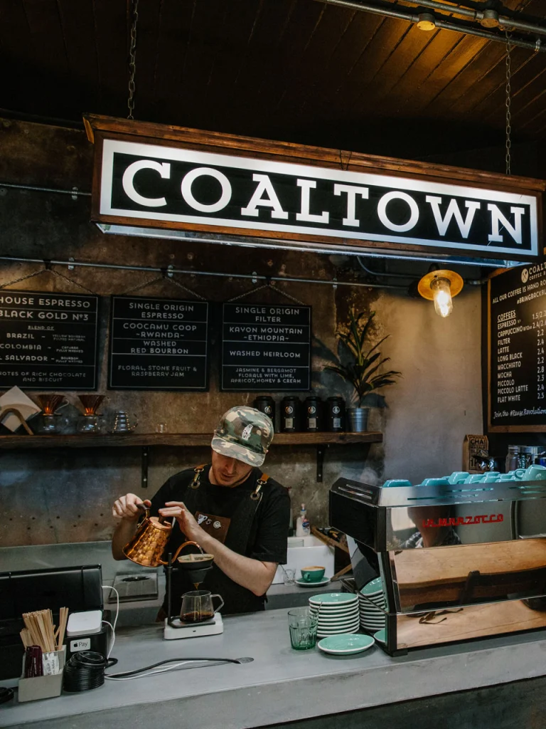 Male pouring coffee behind counter