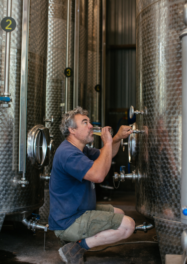 Andy Hallett samples cider from one of the large, silver storage tanks.