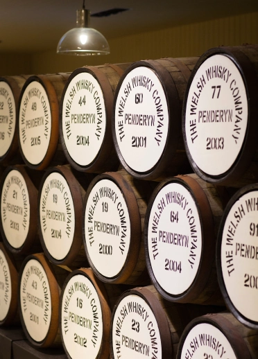 stacked barrels of Penderyn whisky. Each barrel is branded with the phrase 'Penderyn. The Welsh Whisky Company'